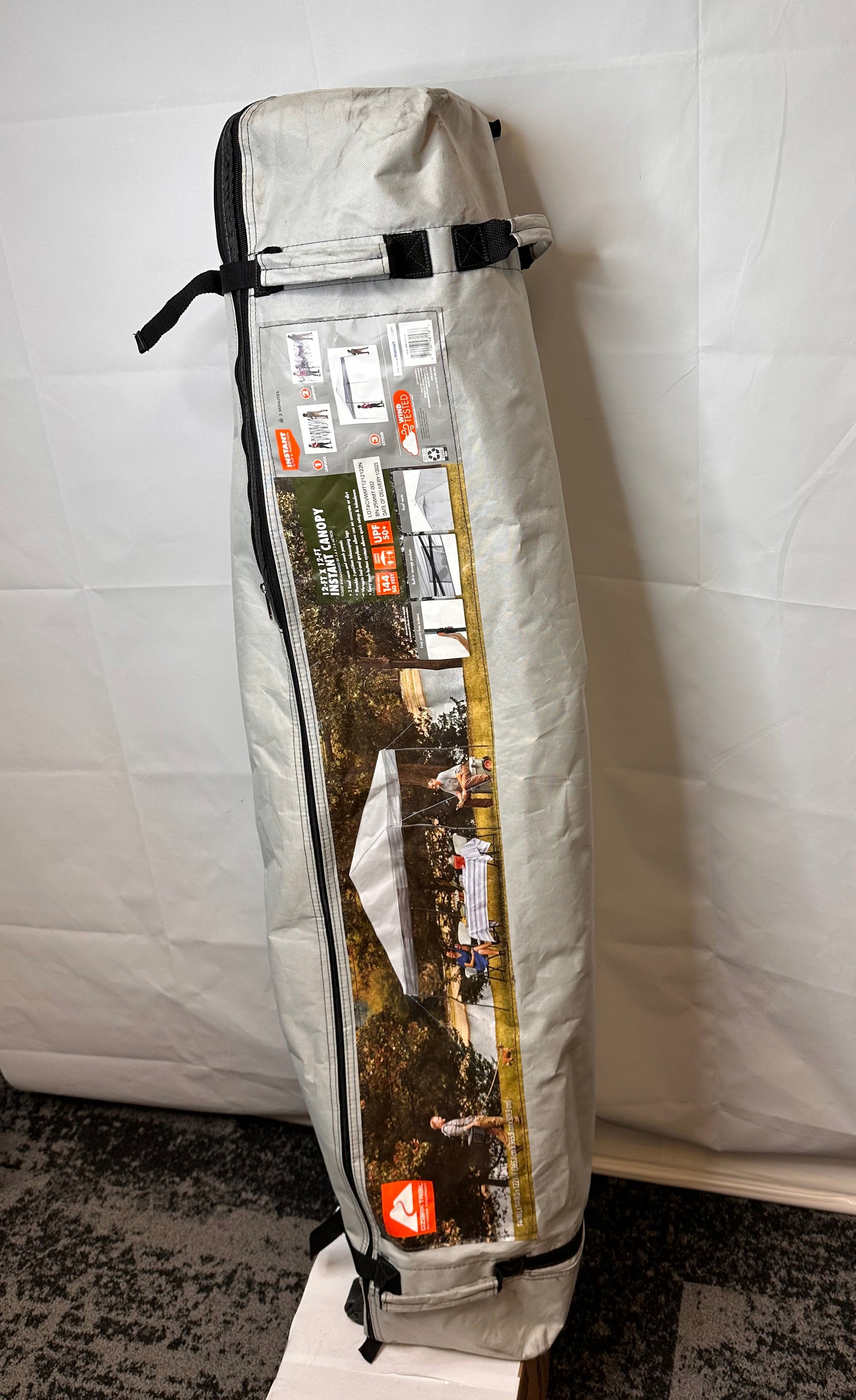 Wheeled carry bag for 12' x 12' Ozark Trail straight leg canopy frame, light gray fabric bag with zipper and straps, showing dirt marks from storage and handling