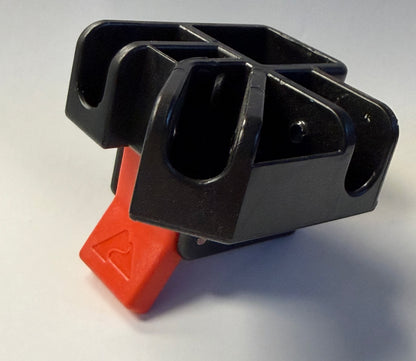 A black plastic multi-groove holder or clip with a bright red triangular push-button switch on the front, photographed on a neutral light gray background.