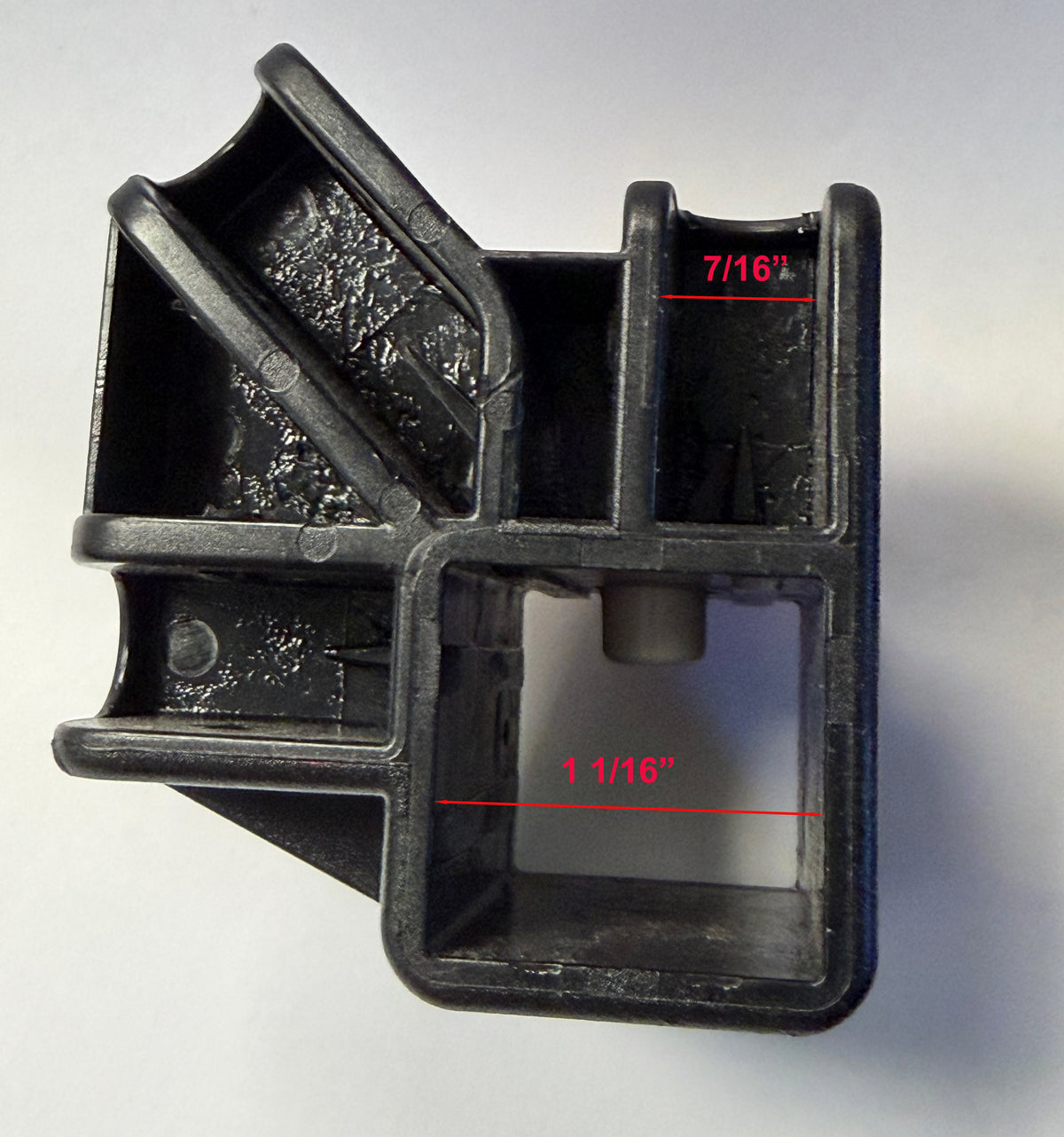 A black plastic multi-compartment container or mold base with red dimension lines and text labels indicating measurements of 7/16 inches and 1 1/16 inches on a plain light background.
