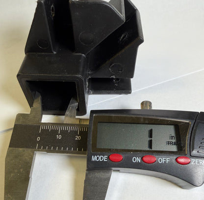 A black plastic square block part shown next to a digital caliper and a digital micrometer, indicating its dimensions are approximately 1 millimeter.