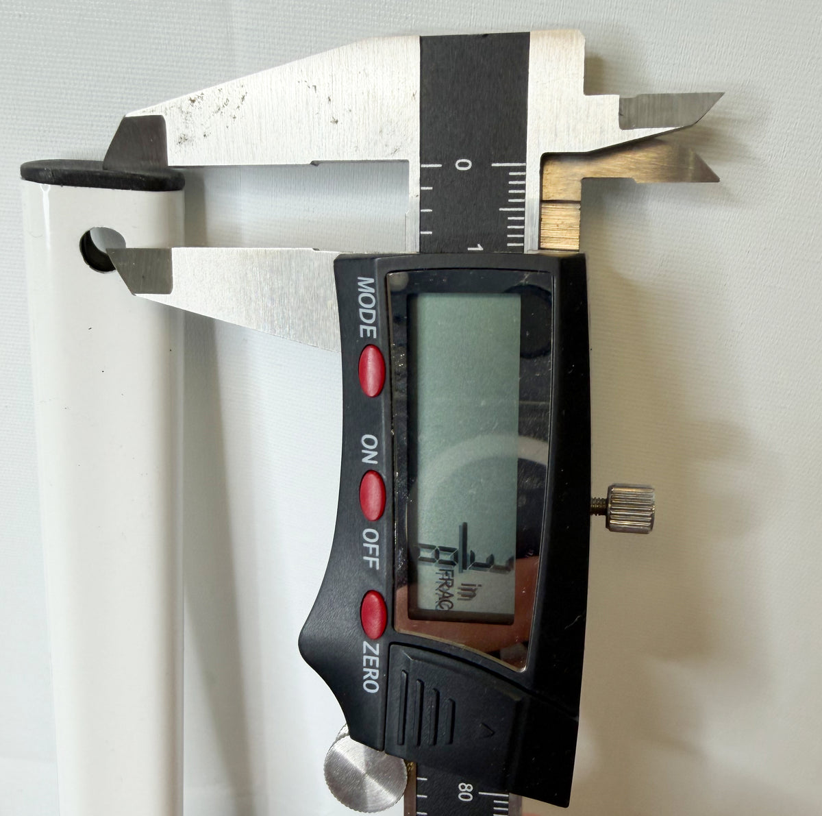 Digital caliper measuring the screw-mounting hole near the end of the white truss bar.