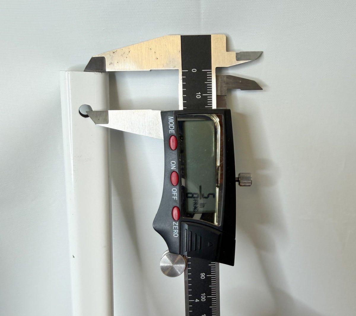 Digital caliper checking the distance between the mounting hole and the end of the canopy truss bar.